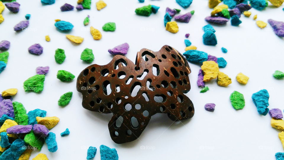 pendant butterfly from coconut on a background of multi-colored stones