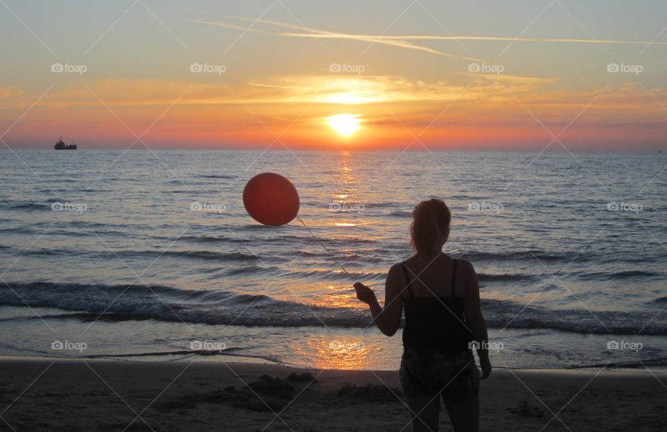 Hope. Woman holding a balloon and look at beautiful sunset