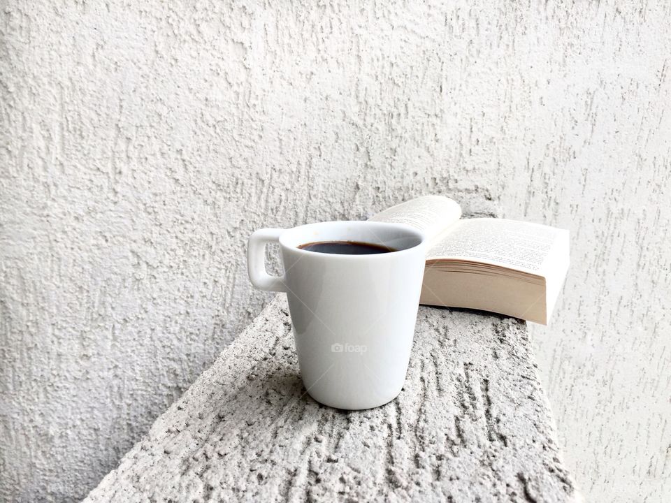 White cup of coffee and book with a white minimalistic background 