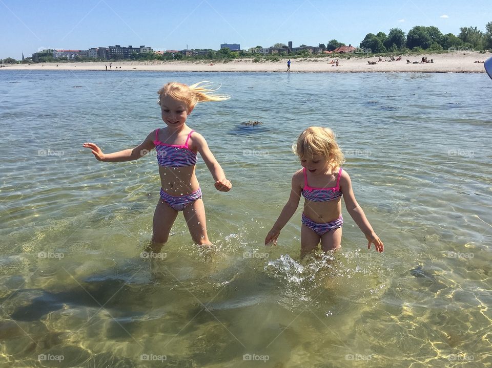 Twolittle sisters age three and five feeling the water at Ribban beach in Malmö.