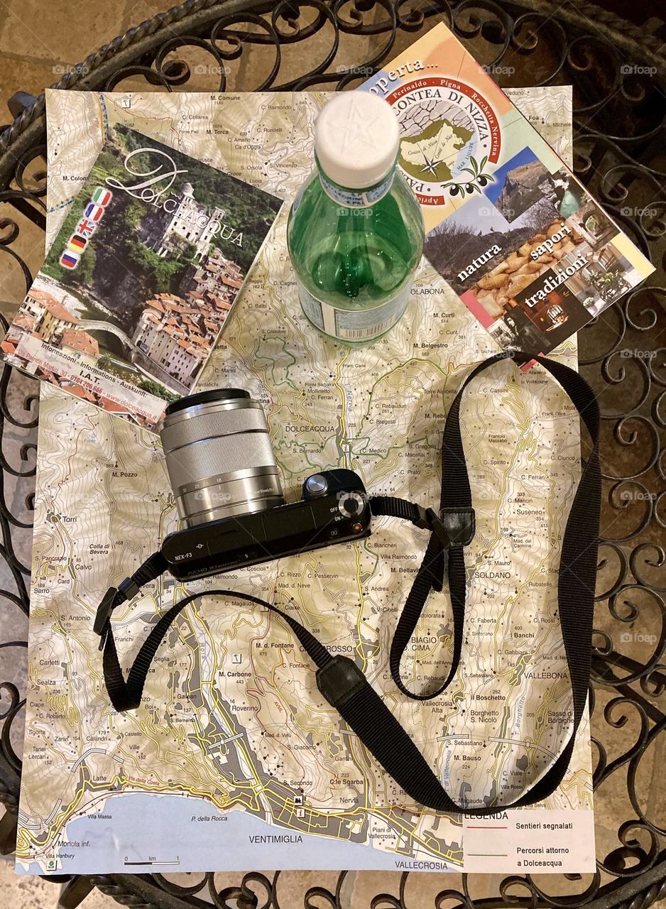 Top down shot of a Sony camera, sparkling water and a map of Dolceacqua, Italy and surrounding area.