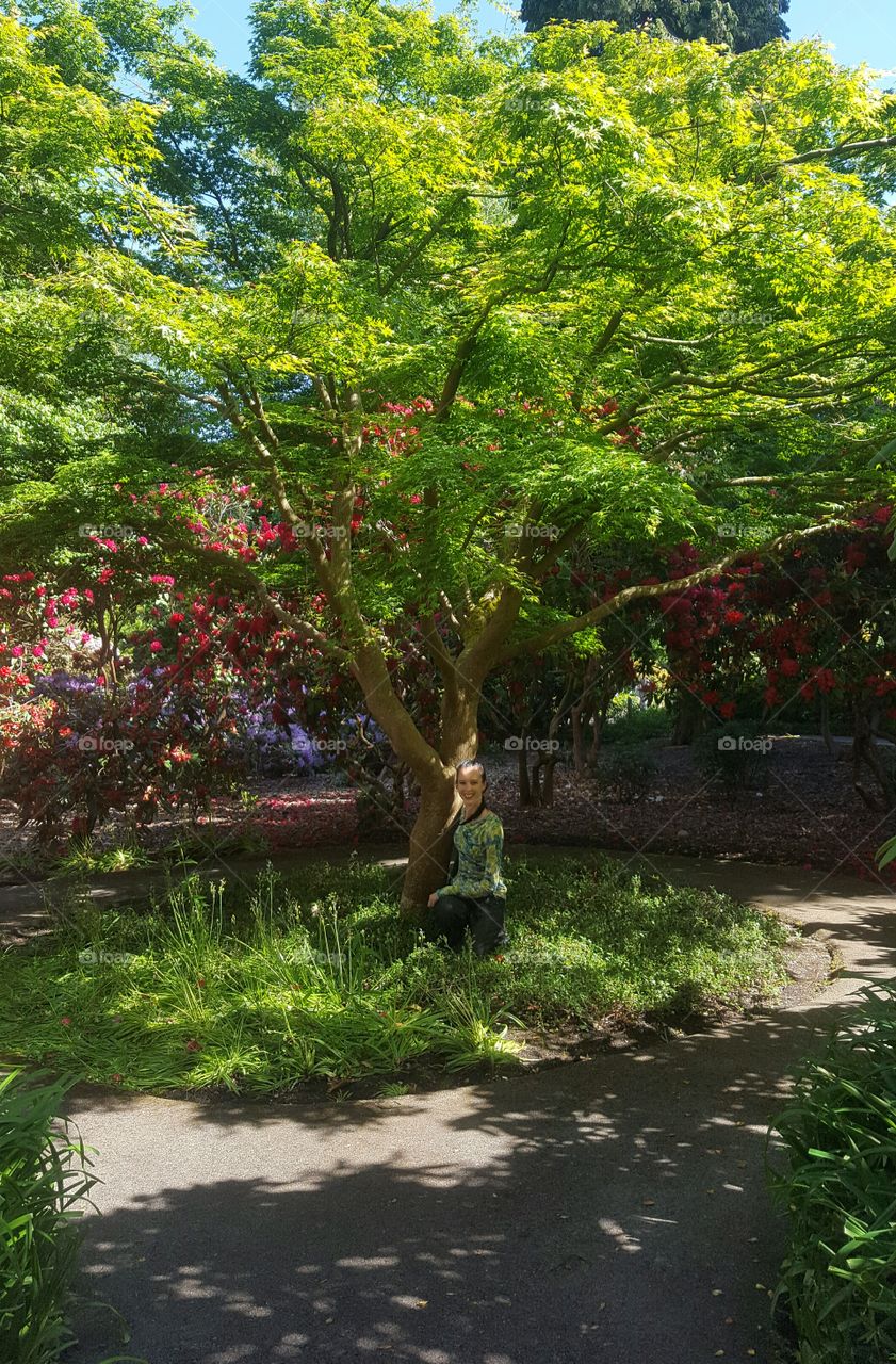 Woman crouching beneath a tree on a hot summer day.