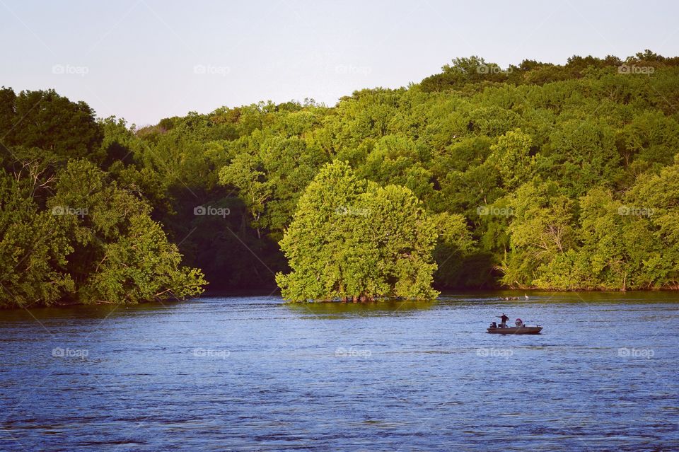 Distant view of a person fishing on river