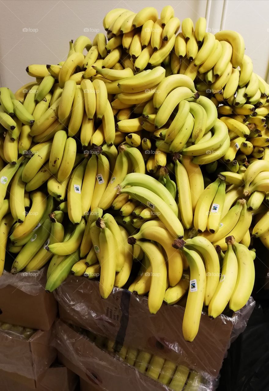 Plenty of a little bit raw bananas on the brown cardboard boxes one upon the other.