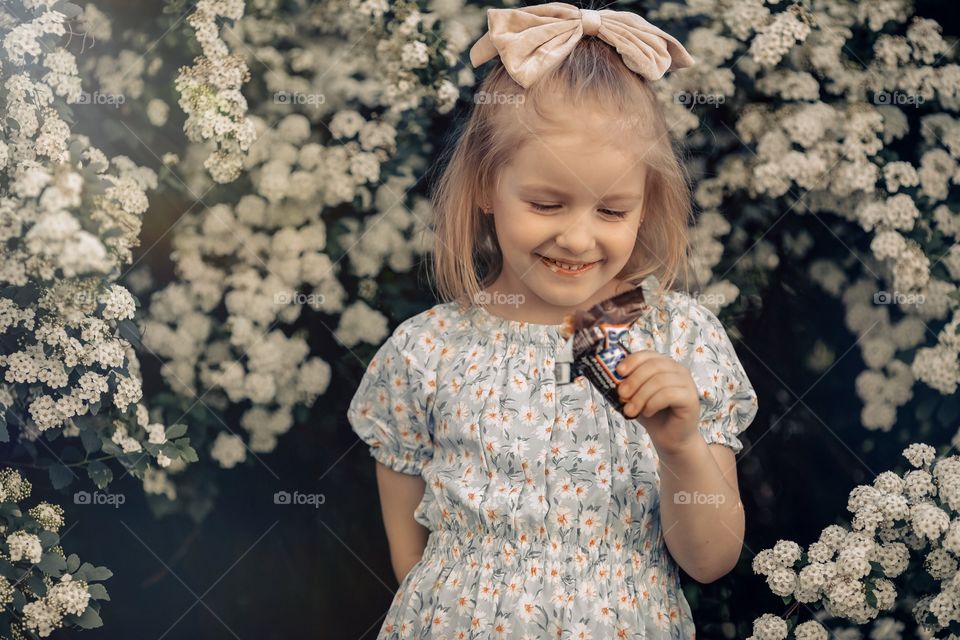 Little girl eating ice cream snickers, smiling face 
