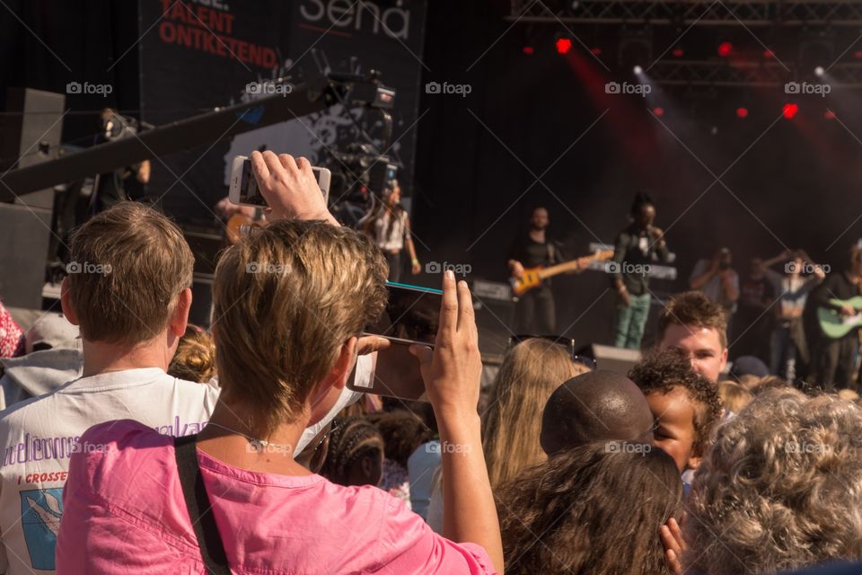 A guy takin pictures with his phone of a concert 