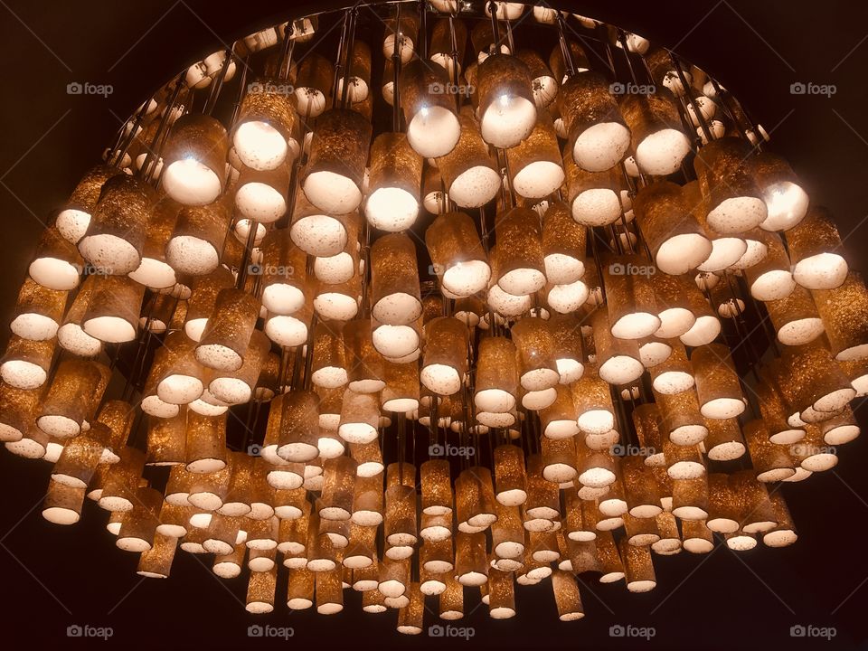 Suspended lighting at the Grove Hotel, Watford. Yellow lights in tubes of varying length clustered together in the round. Seen in Winter.