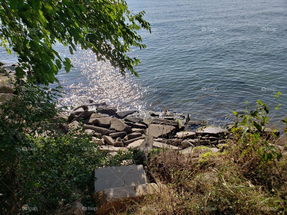 rocks at the edge of a lake on a sunny day