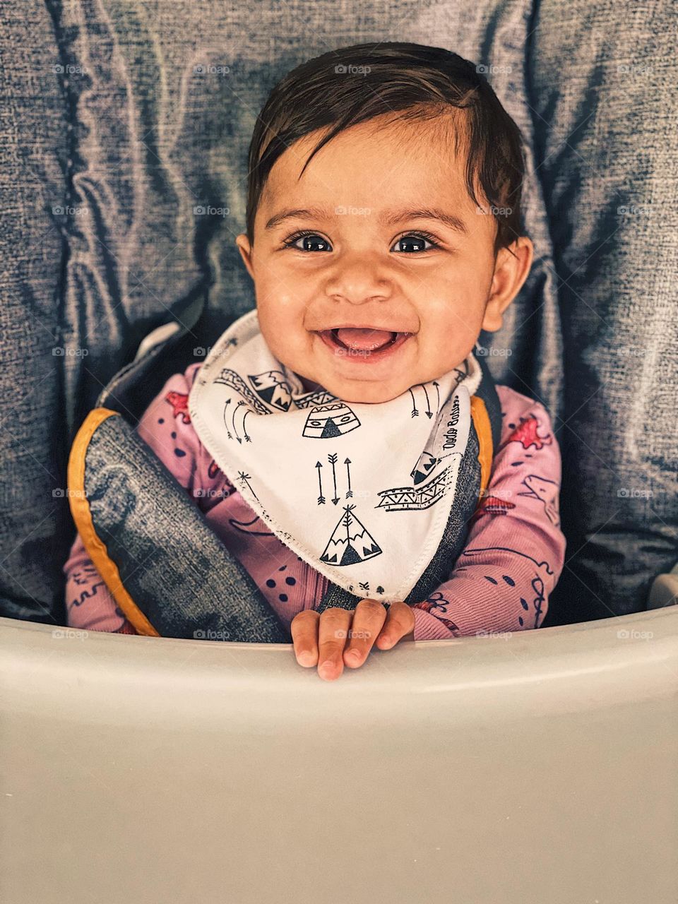 Baby smiling in happiness while sitting in high chair, baby happily waiting for food, cute baby girl smiling, facial expressions of happiness, showing the emotion of happiness, baby is happy with mother, portrait of a happy child, portrait of happy