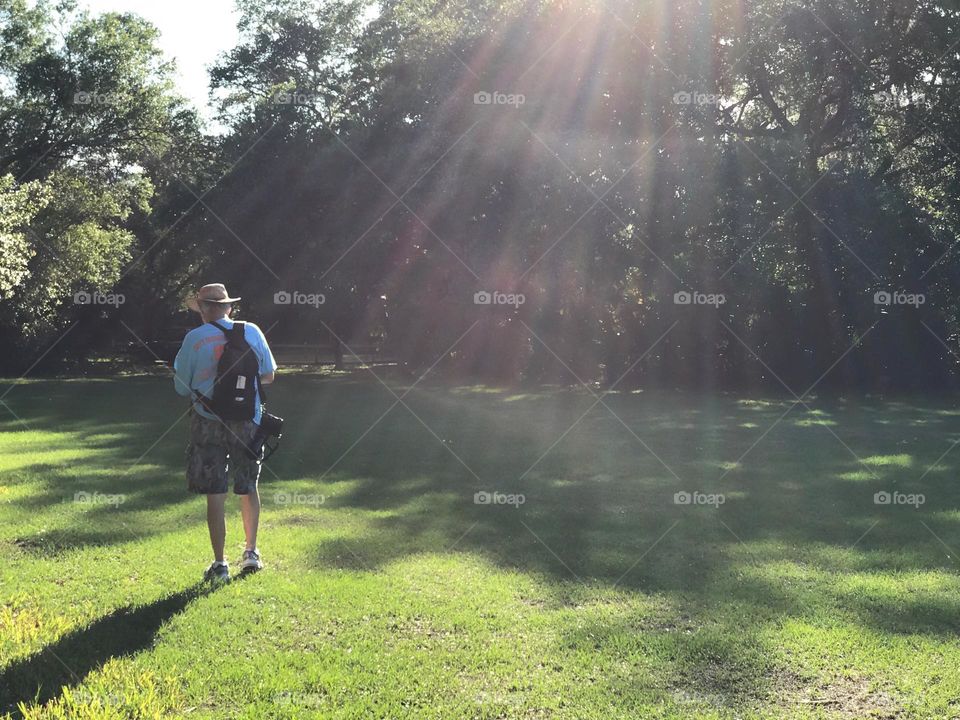 Man hiking through a sunlight rainbow for a day of photography.
