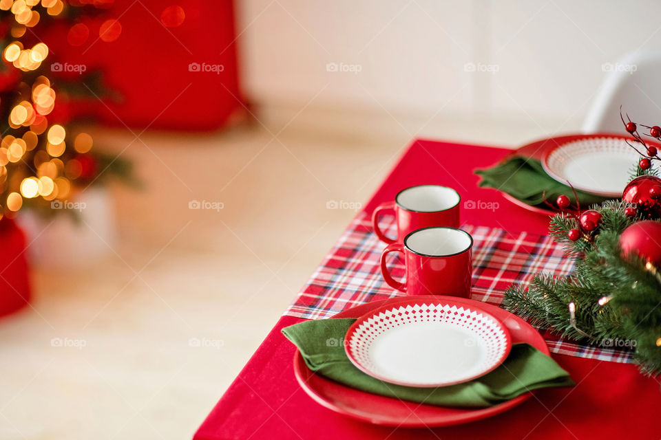 Festive winter cozy kitchen interior with garlands, decorations and gifts.  Christmas dinner at the decorated table.