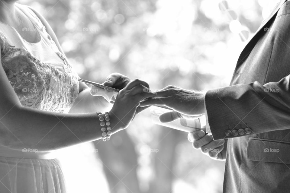 Close-up of bride putting ring on men's hand