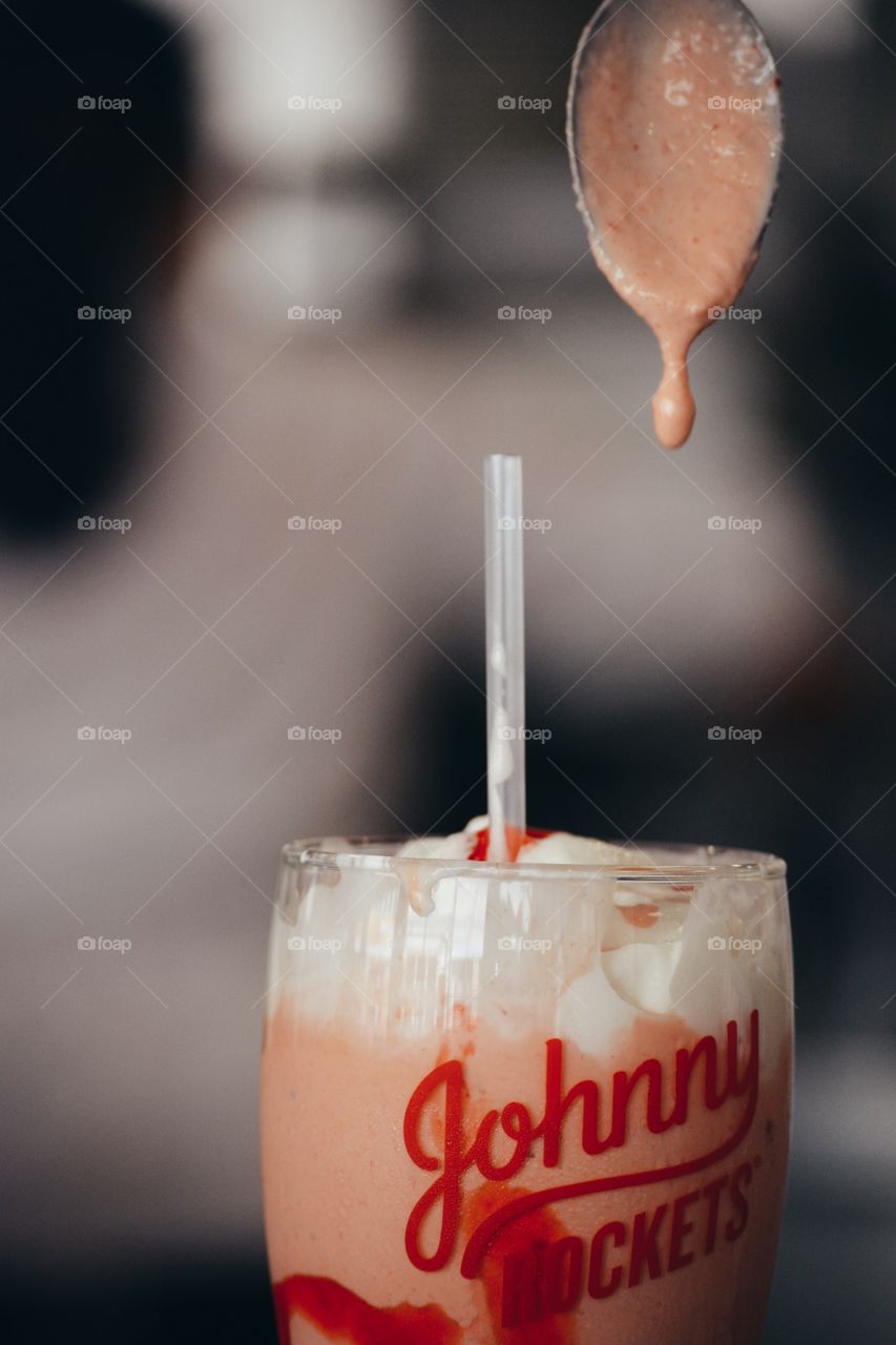 close up dripping strawberry milkshake from spoon straw and whipped cream strawberry sauce cream milk yummy drink retro vintage diner blurry background 