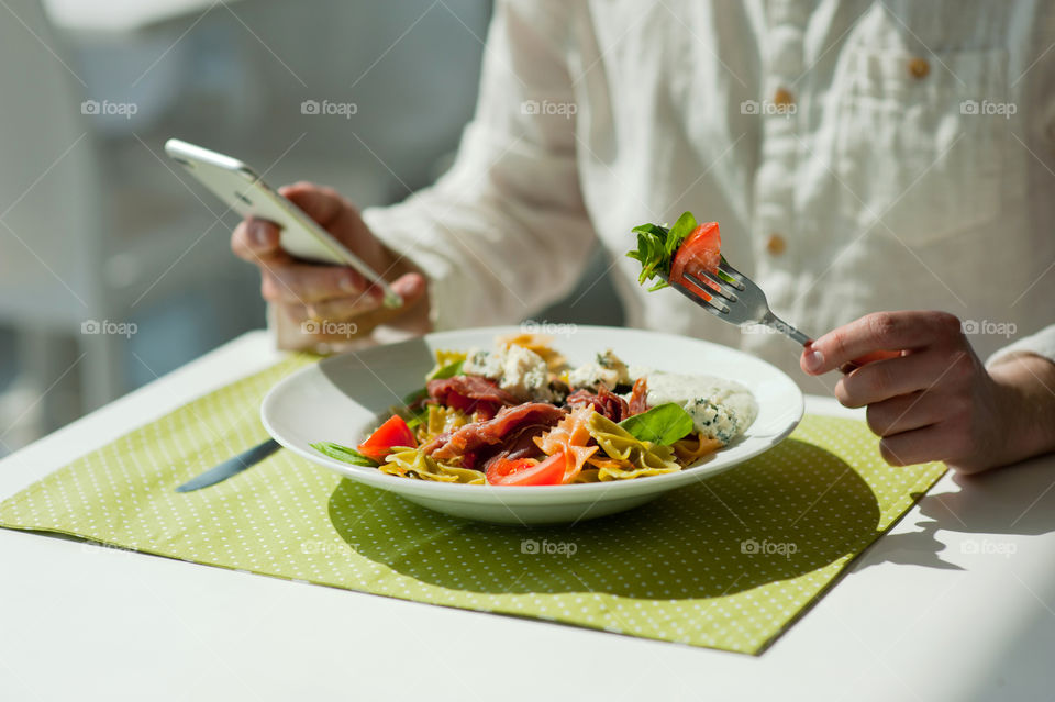 close-up of a young man eating a salad in a light kitchen