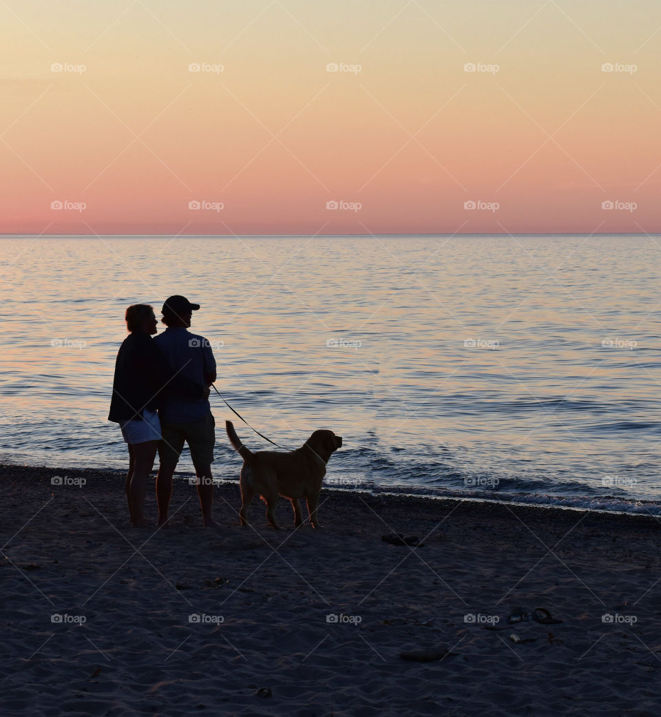 Heterosexual couple with dig on the beach at sunset