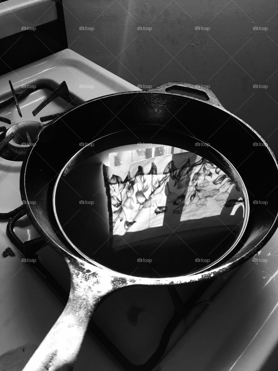 Frying pan with oil placed on stove; provides reflection of window adjacent to stovetop; grungy edge, Black and white filter increases detail; moderate contrast 