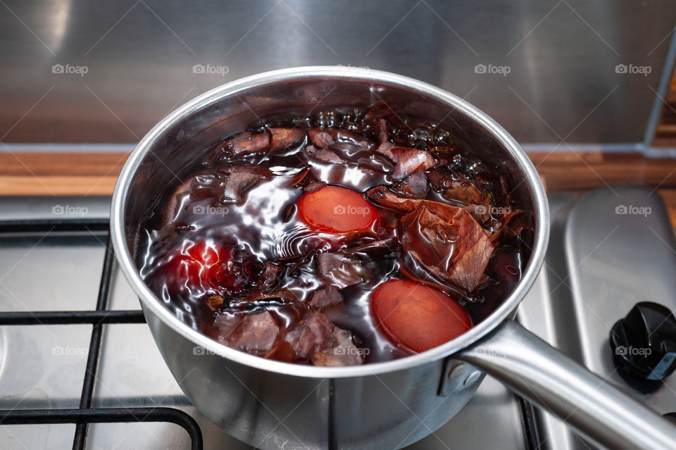 Easter eggs together with onion peels slowly cooking in metallic pot in order to naturally dye eggs with earthy rustic brown colour.