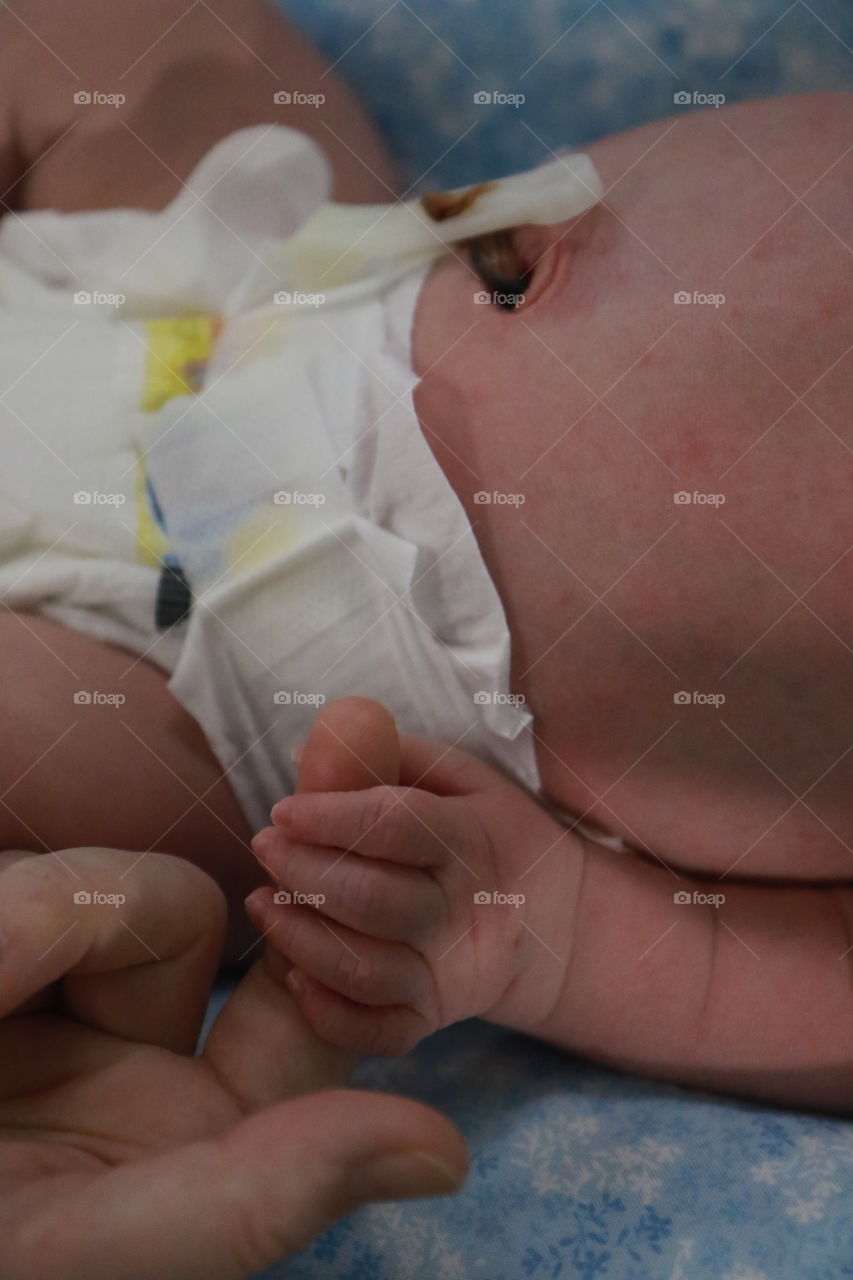 Baby holding finger in a humidicrib close up
