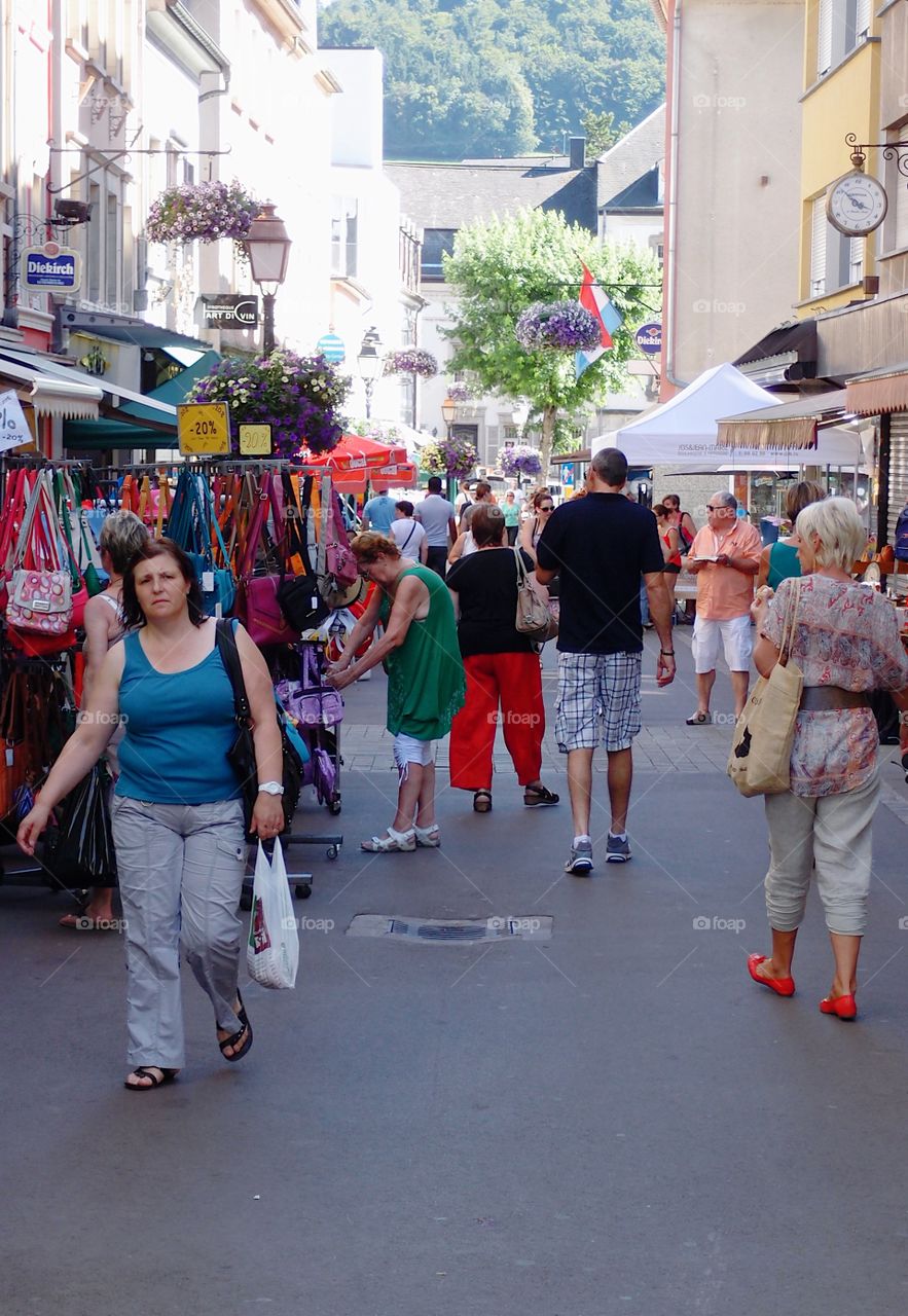 Crowds of people out walking, shopping, and eating, on European streets on a summer day. 