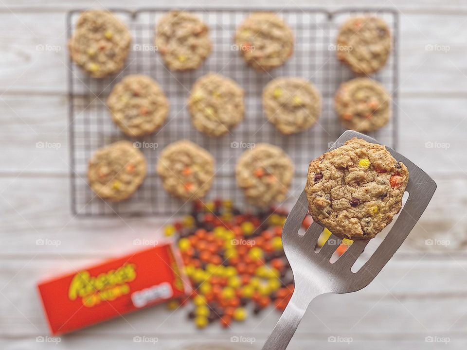 Freshly baked cookies on a cooking rack, placing cookies on a cooling rack with a spatula, Reese’s Pieces Chocolate Chip Cookies, baking at home, fresh homemade cookies, food photography with a mobile phone, smartphone photography, delicious cookies