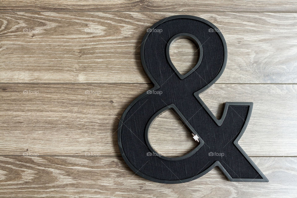 Diamond engagement ring on an ampersand with a wood background