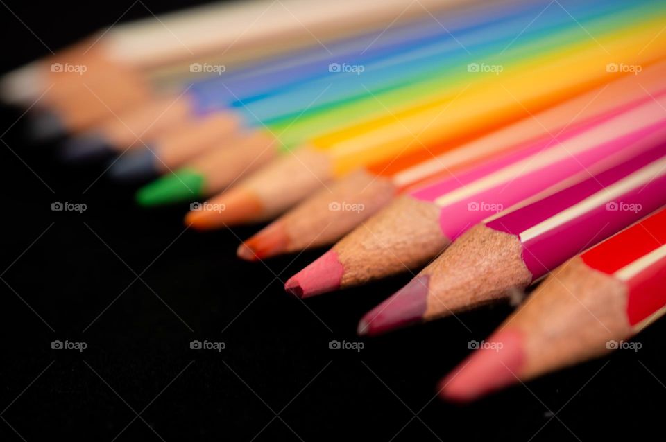Colored pencils in a row with a black background