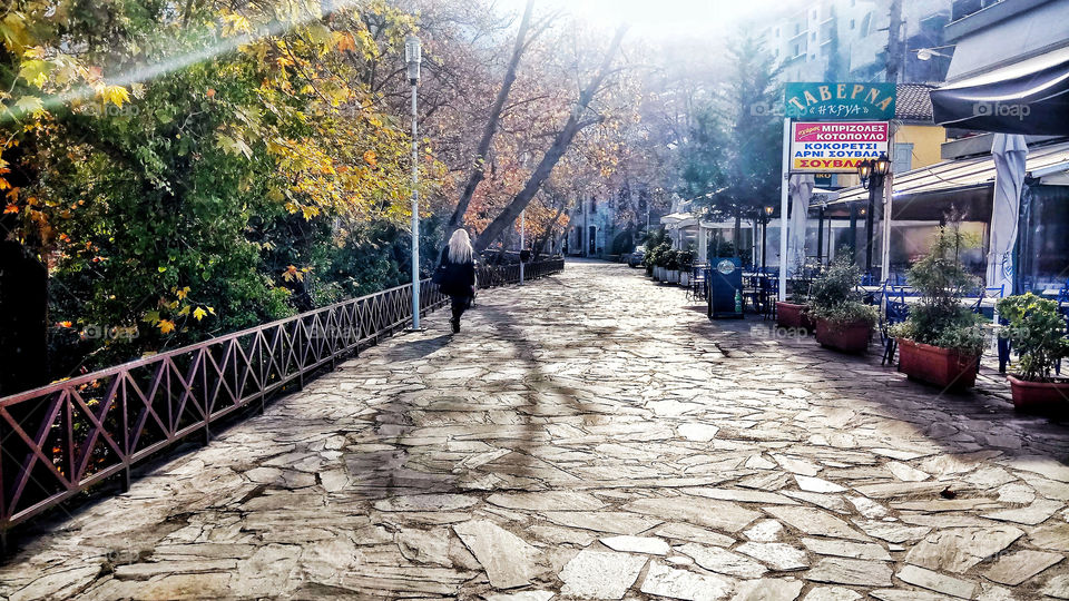 A woman is crossing a beautiful paved road at noon in Piges Kryas,Livadeia