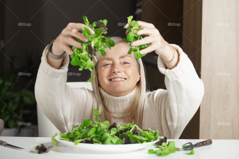 Mature woman holds green lettuce