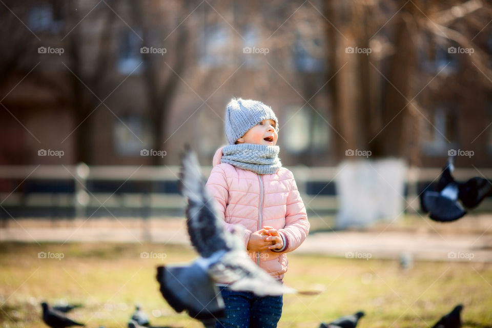 Little girl with pigeons in spring park