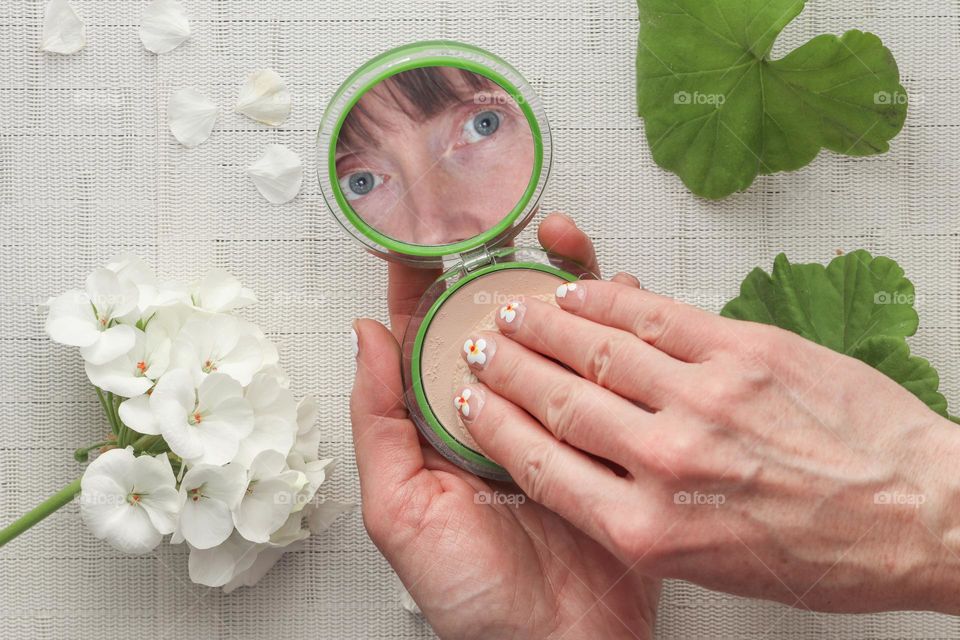 Caucasian woman is using her makeup  powder