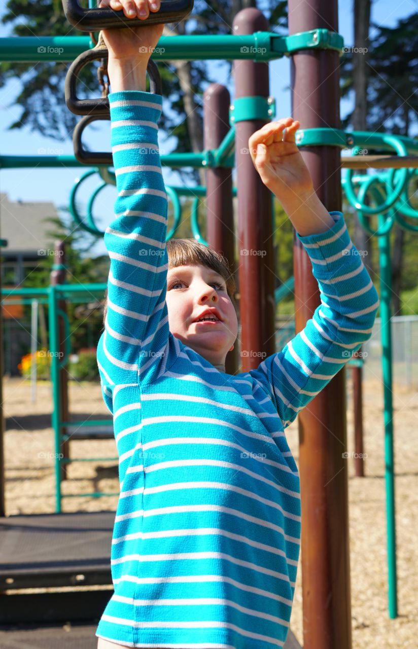 Boy Swinging On Monkeybars