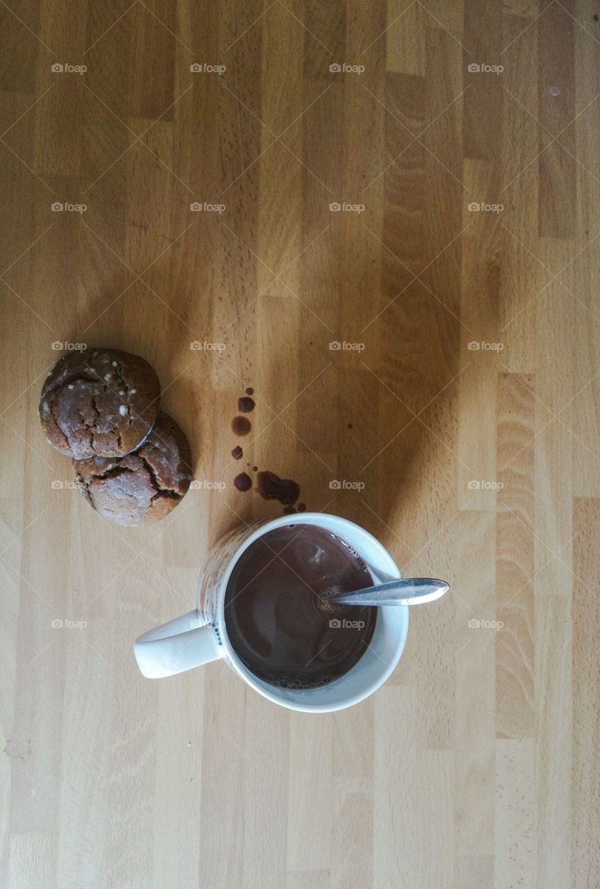 A cup of hot chocolate with a bit of spilage and two homemade cookies