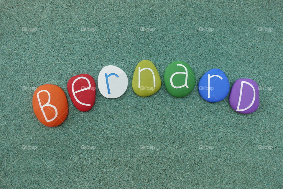 Bernard, masculine given name composed with multi colored stones over green sand