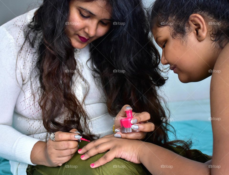 Mother applying nail polish in her daughter's fingers