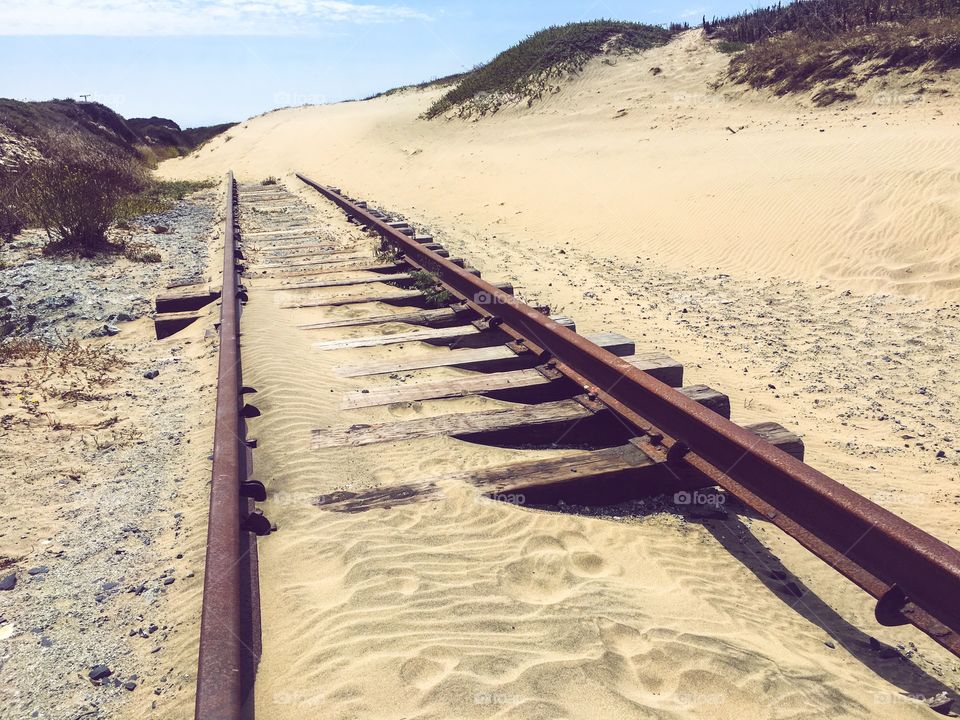 Abandoned railroad tracks leading into sand dunes