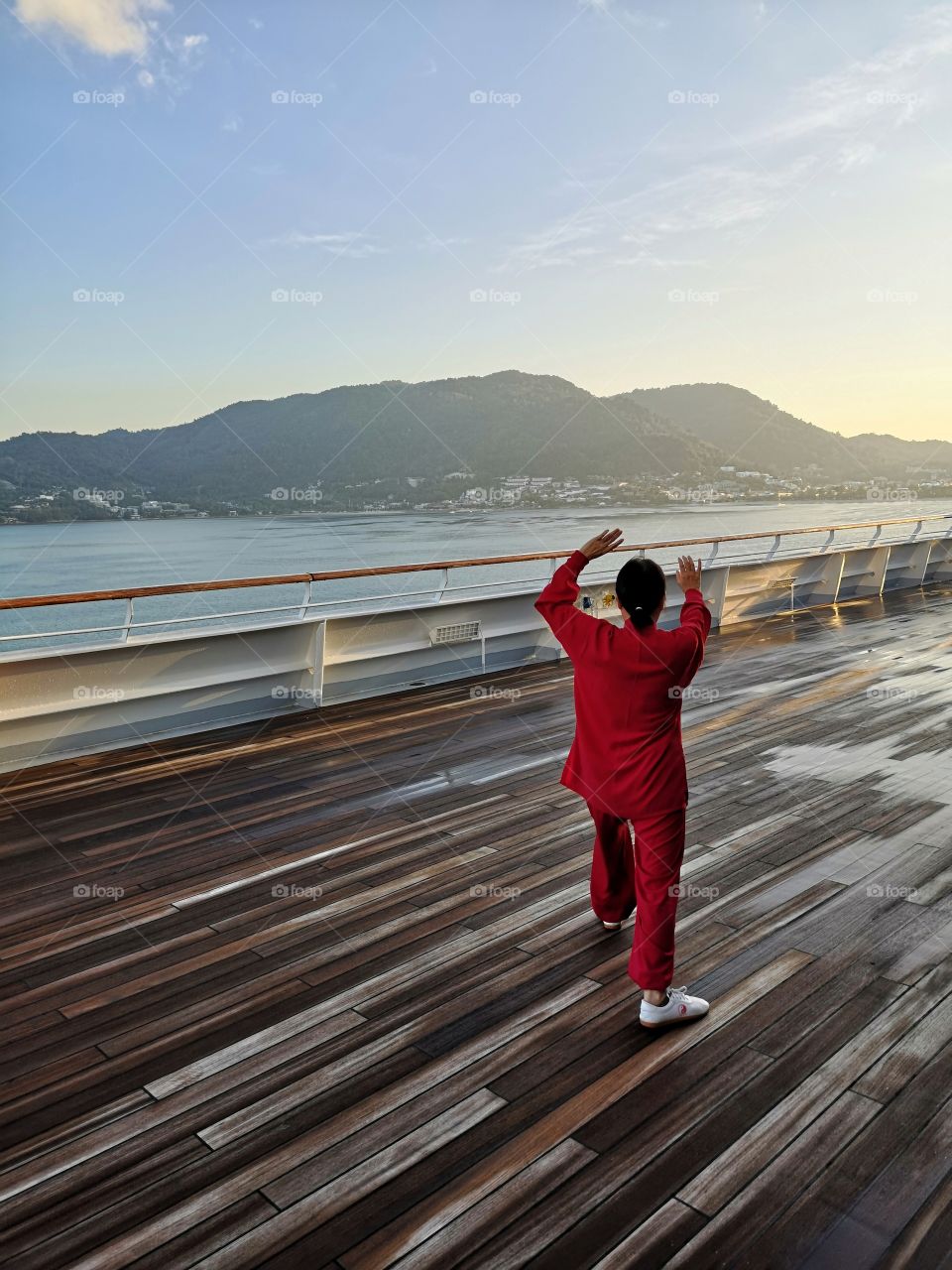 woman from behind practices tai chi on the deck of a ship