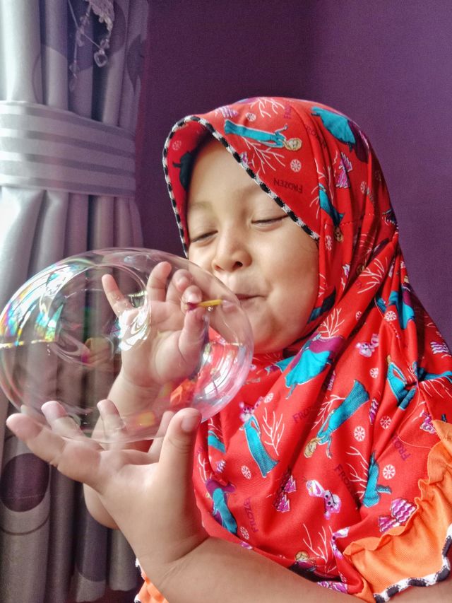 A little girl is playing blowing up balloons.