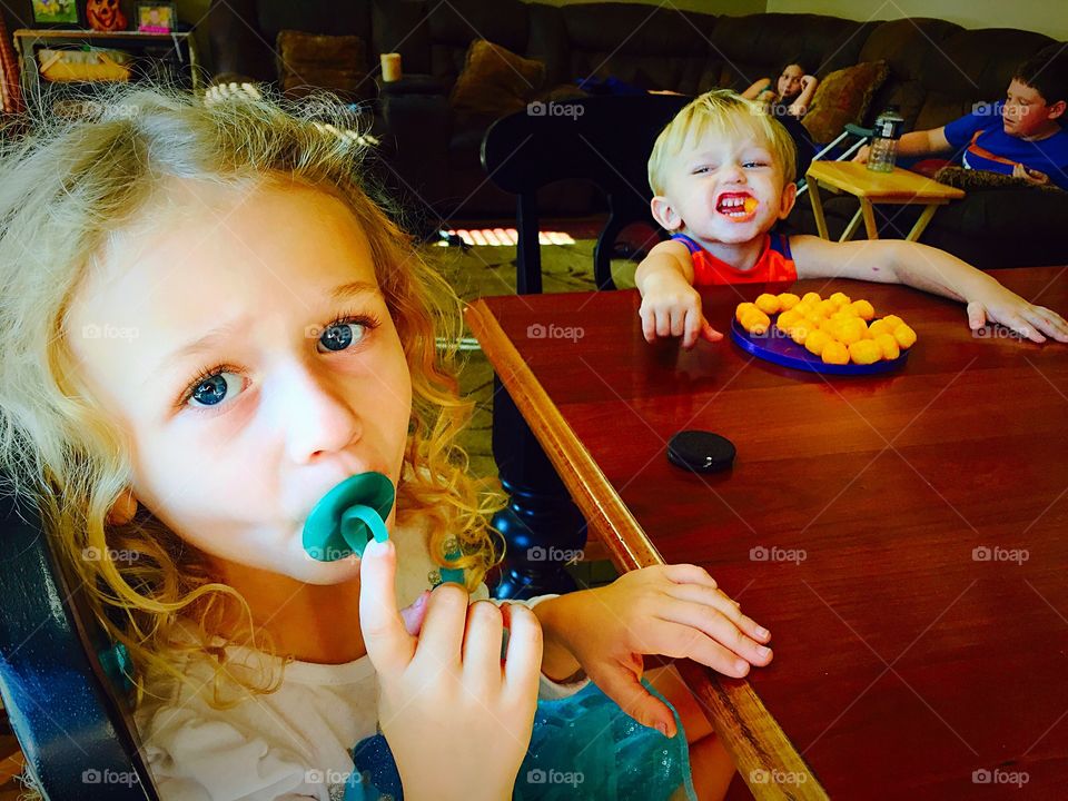 Sibling sitting in restaurant eating cheese balls