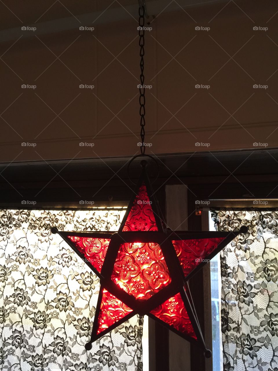 Red glass star hanging in the window with sunlight shining through