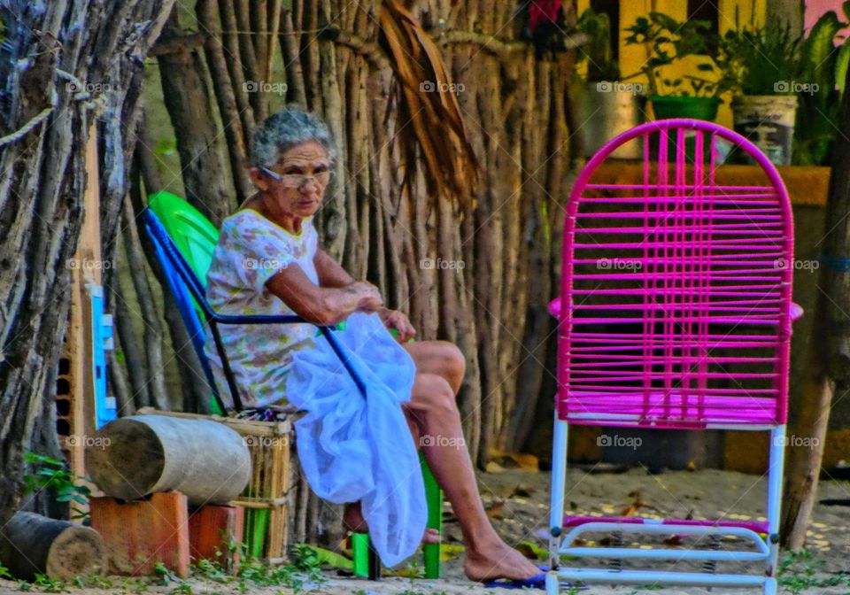 An old woman sewing. An old woman sewing in the country side of Brazil