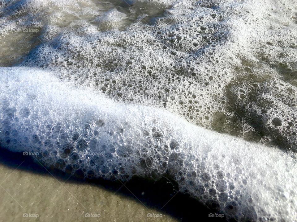 Closeup of foaming wave breaking on sand 