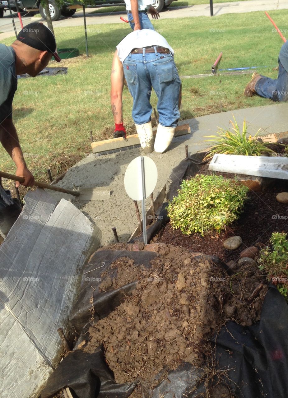 Workers creating a cement sidewalk.  Boots in cement too.