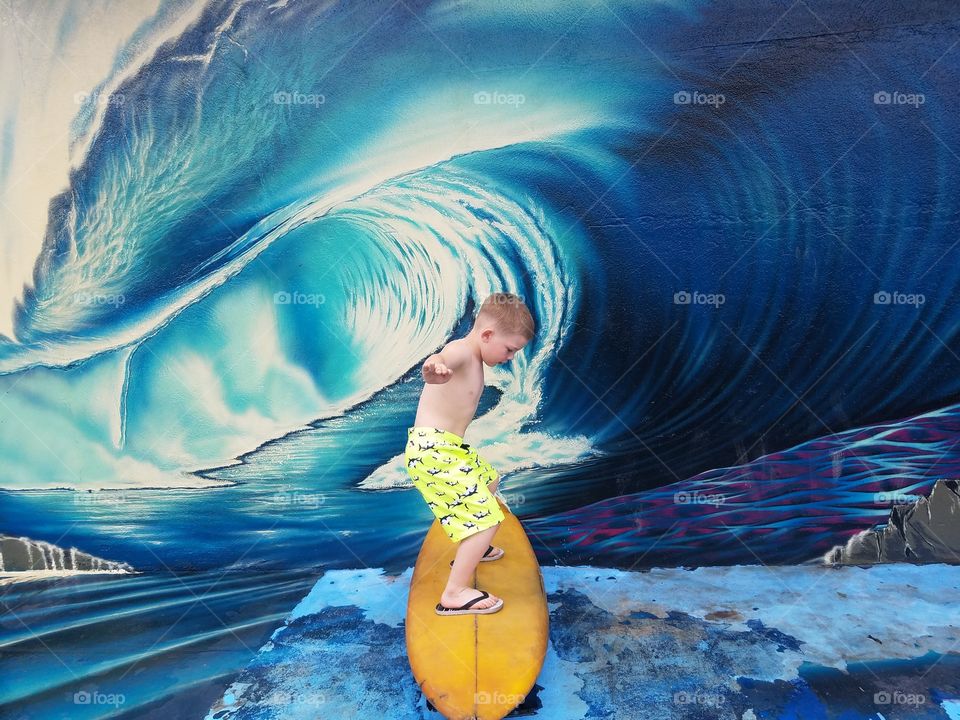 Boy has fun with this mural outside a north shore surf shop.