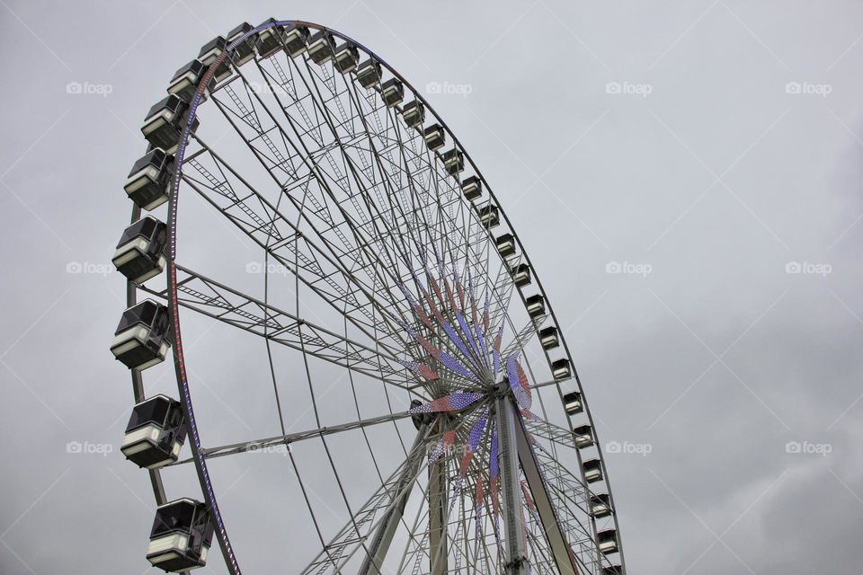 Big metal Ferris wheel on the grey sky background 