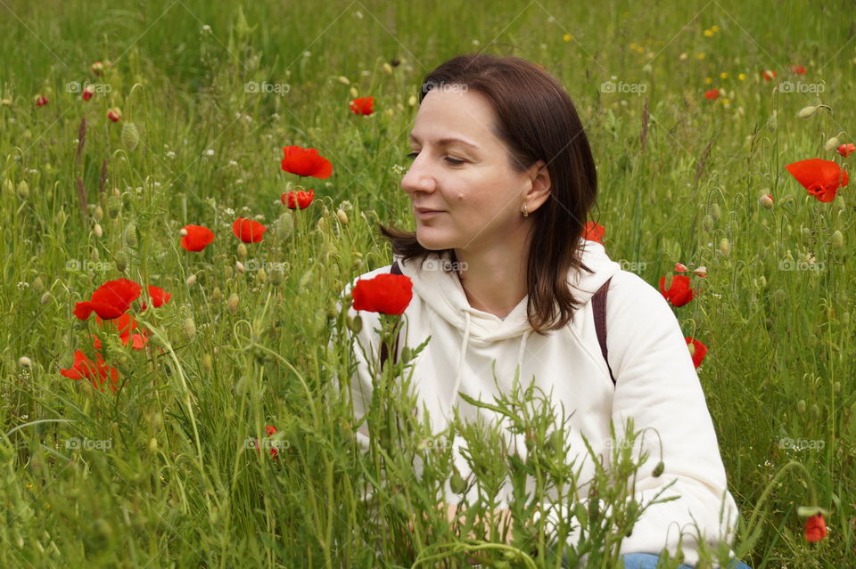 Young woman on a summer meadow with poppies