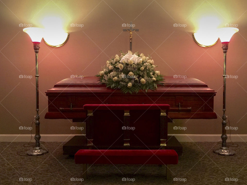 Casket in funeral home with lamps on the side