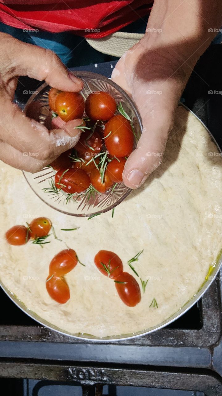 Putting cherries tomatoes in the pizza 