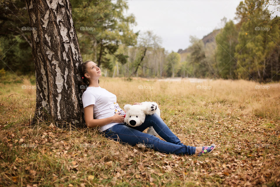 Woman resting on tree and holding toy