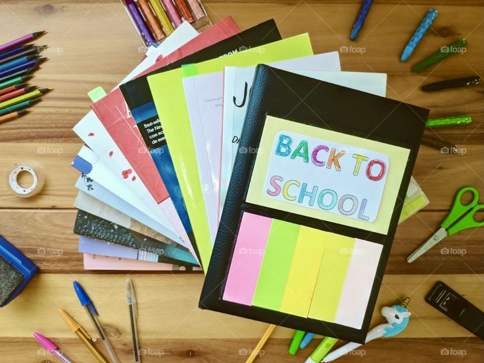 A note written back to school, several colored pencils and books 