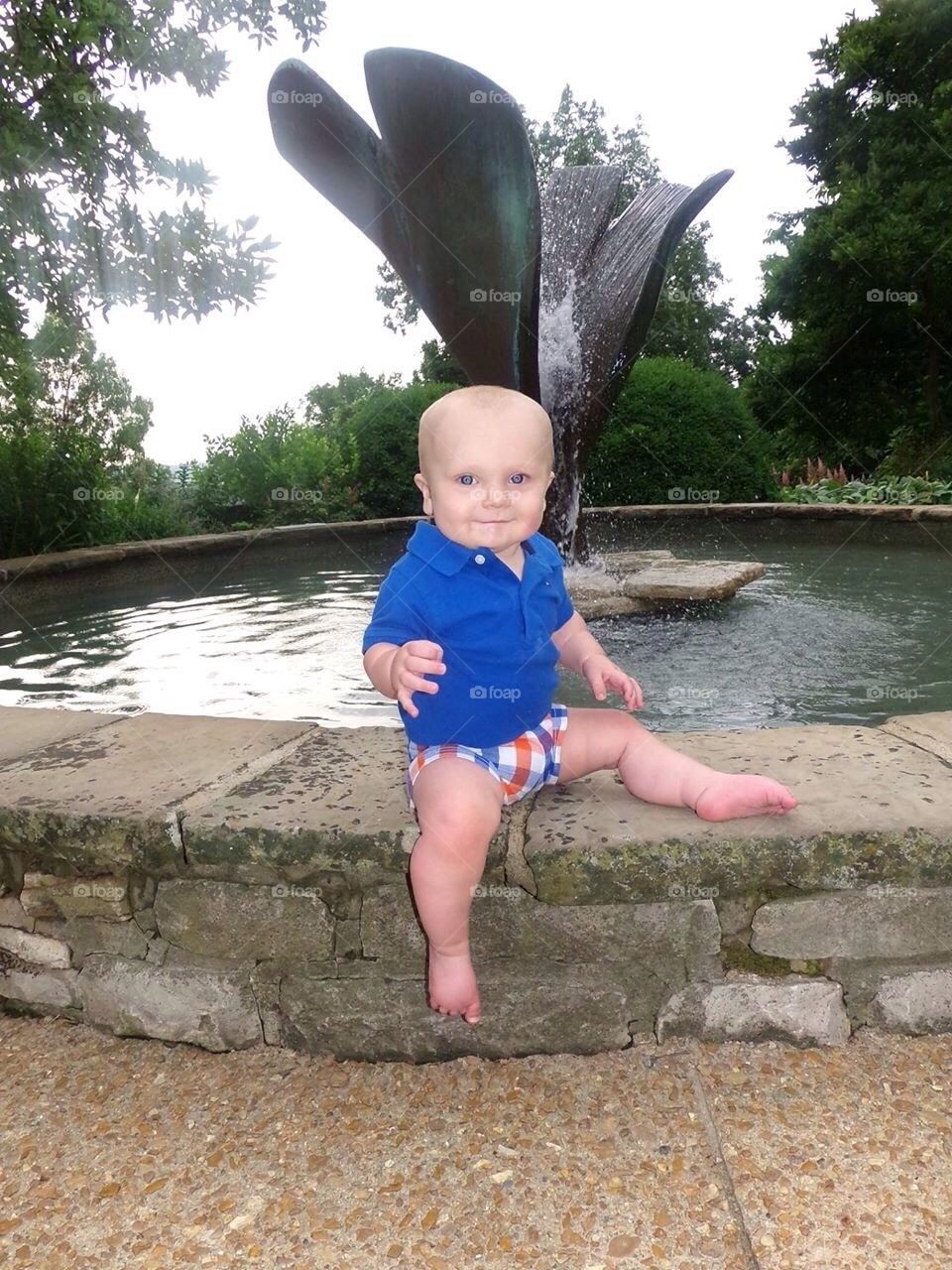 Baby sitting by fountain